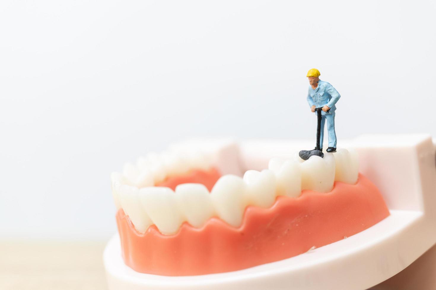 trabalhadores em miniatura consertando um dente, saúde e conceito médico foto