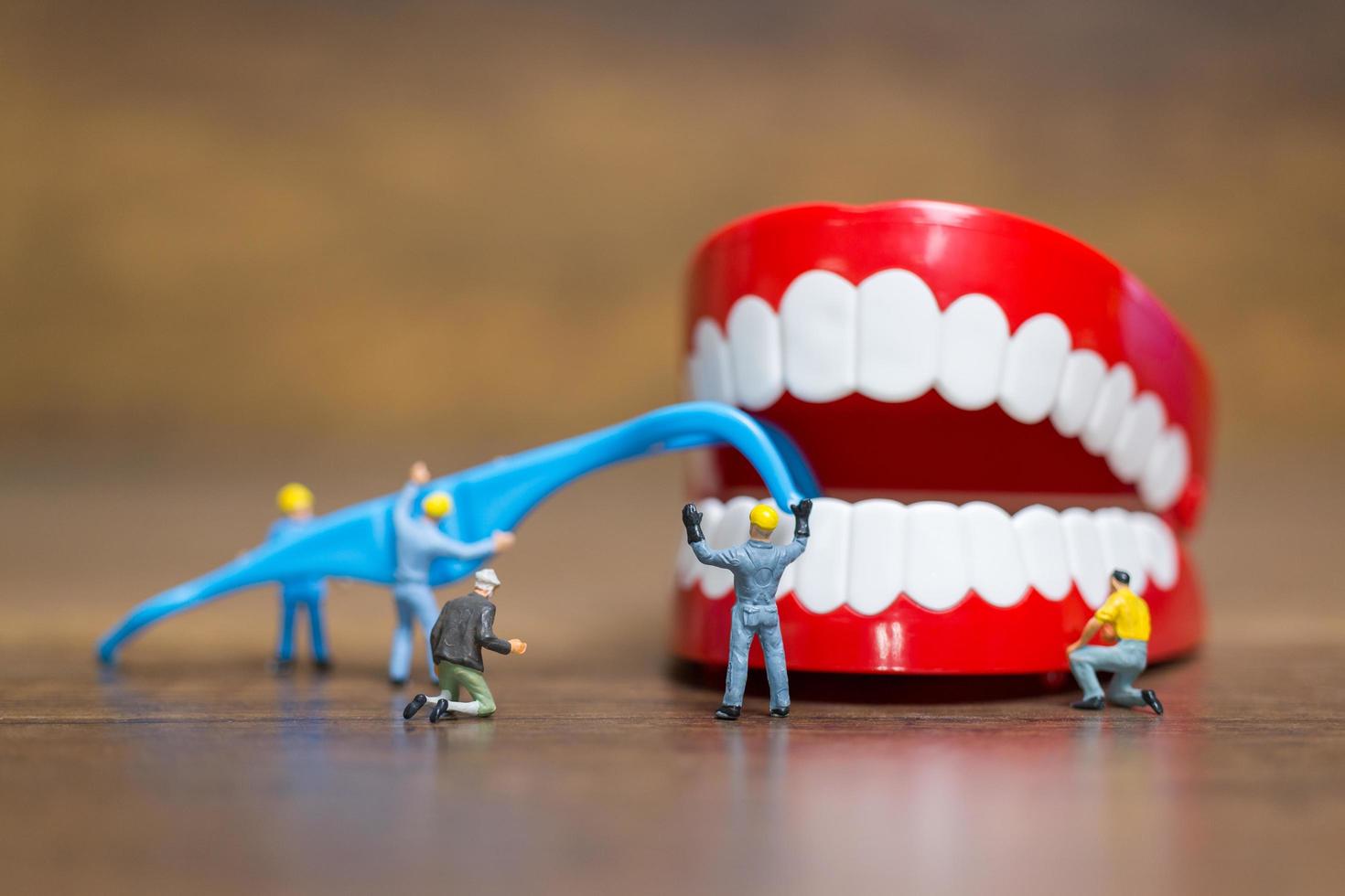 trabalhadores em miniatura consertando um dente, saúde e conceito médico foto