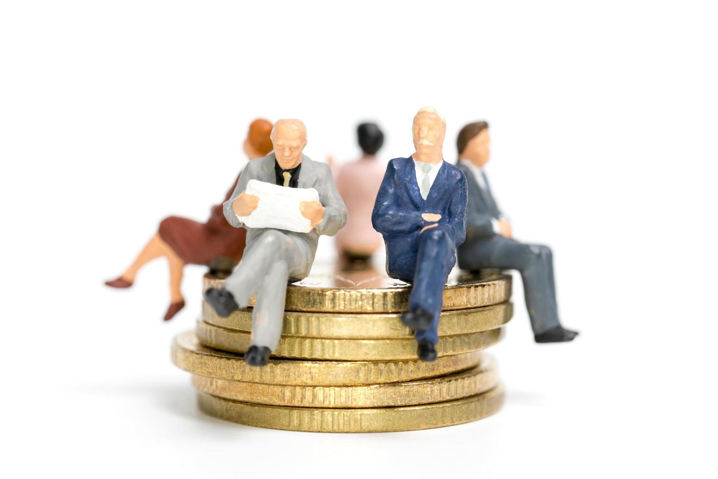 empresários em miniatura sentados sobre uma pilha de moedas, dinheiro e conceitos financeiros foto