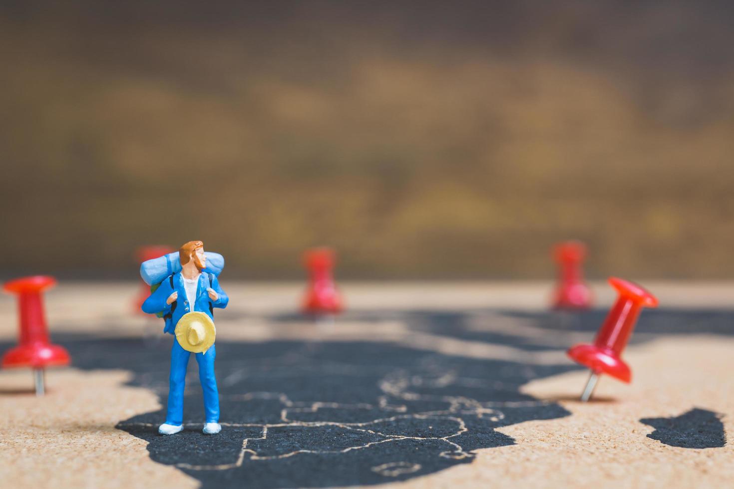 mochileiro em miniatura caminhando em um mapa-múndi, conceito de turismo e viagens foto