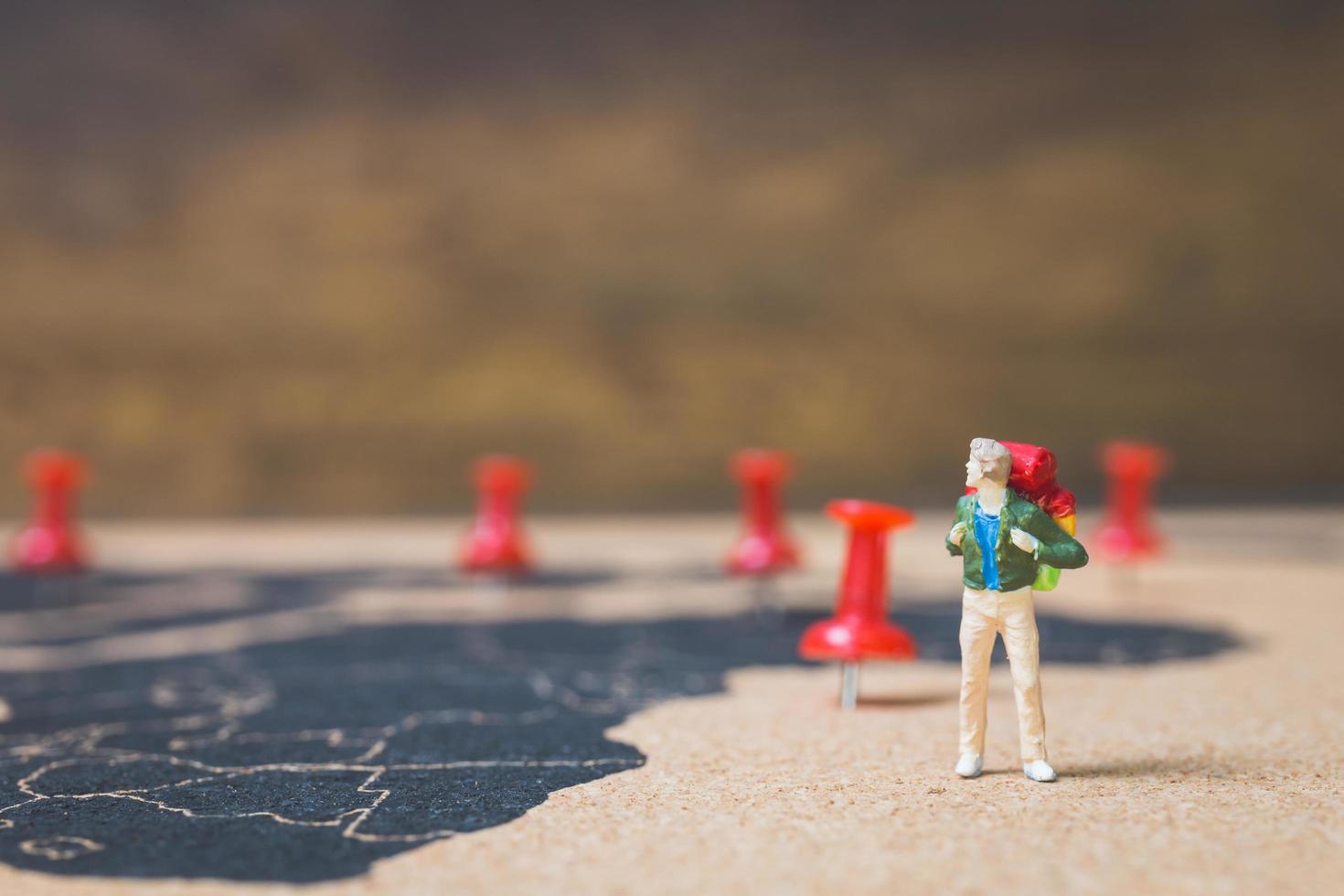 mochileiro em miniatura caminhando em um mapa-múndi, conceito de turismo e viagens foto