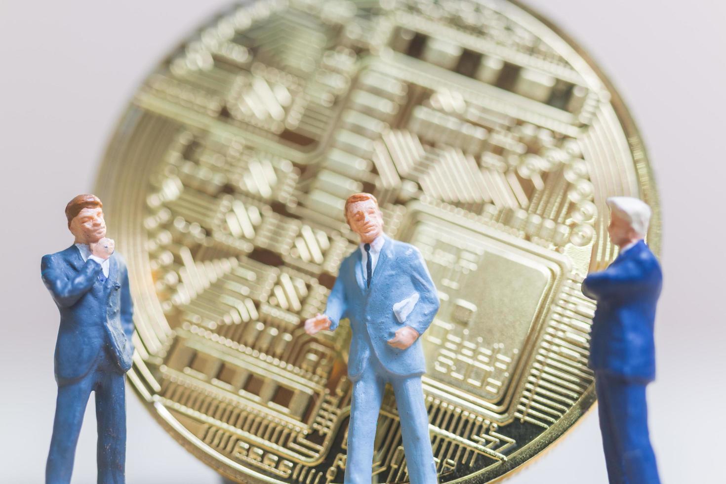 empresários em miniatura em frente a uma moeda criptomoeda bitcoin, conceito de negócio foto