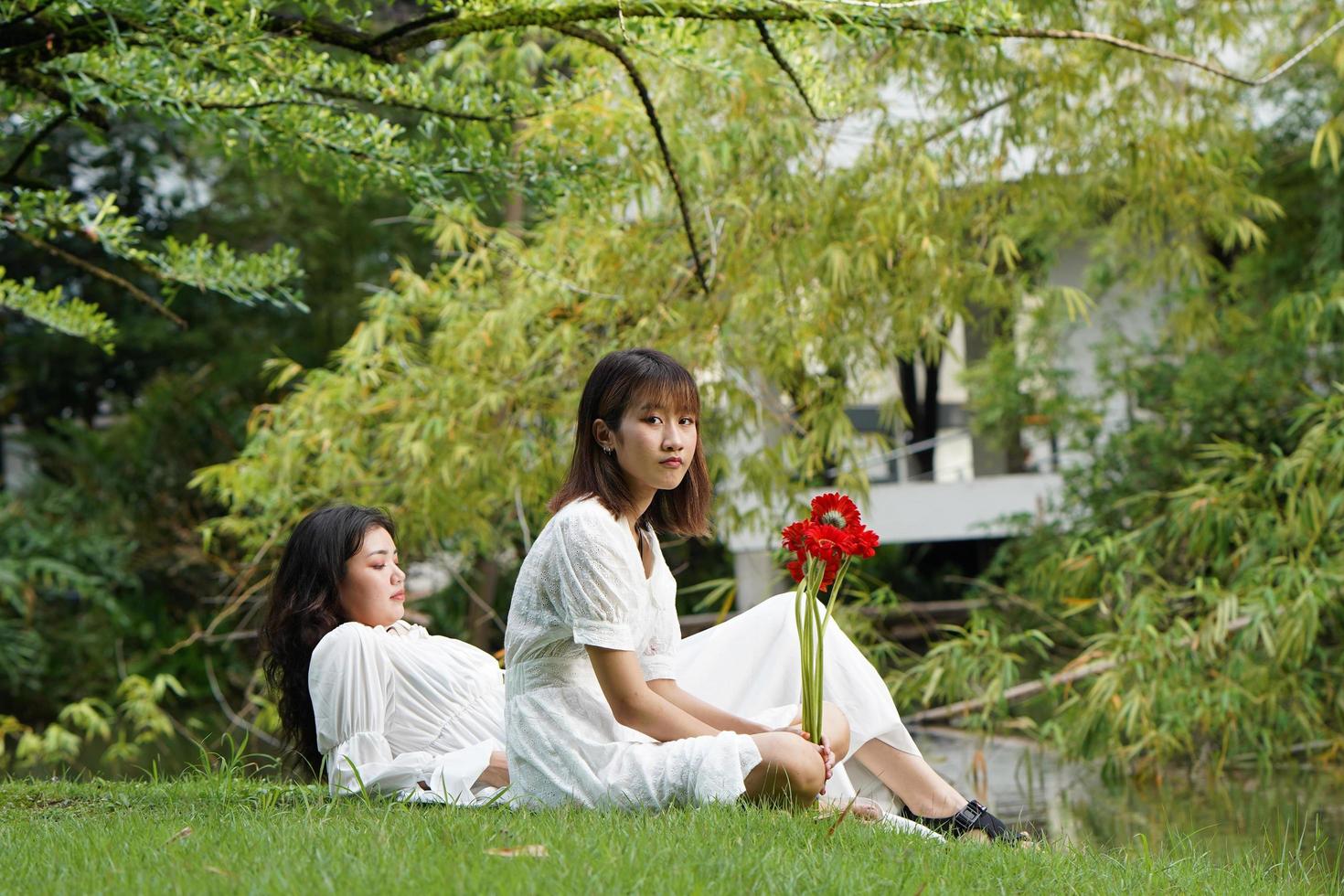 duas mulheres relaxando em um parque com flores foto