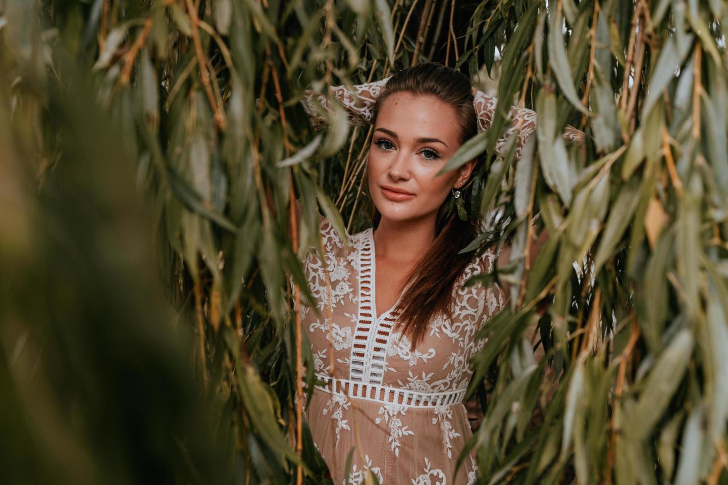 mulher usando um vestido de renda contra as folhas foto