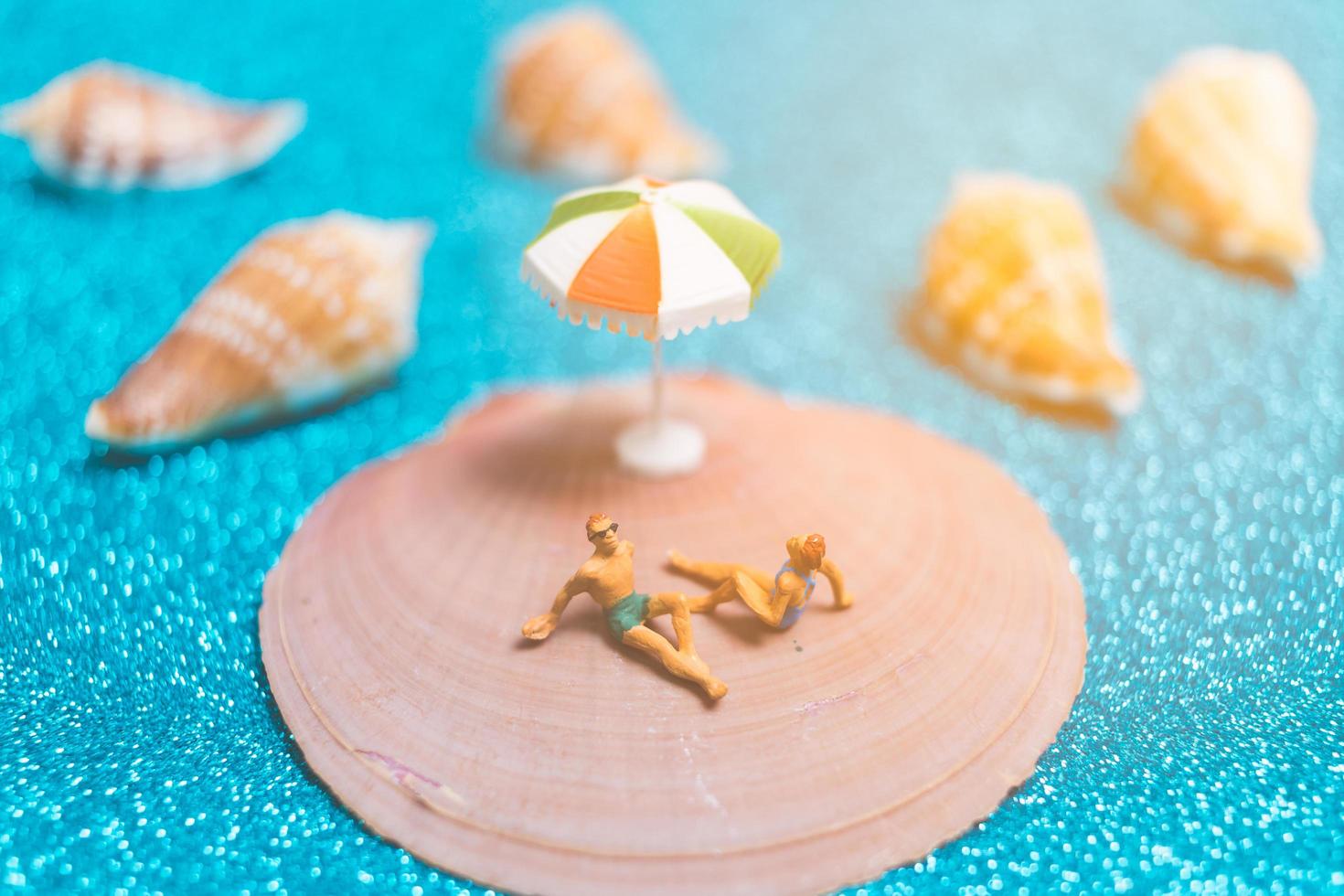 pessoas em miniatura usando maiôs relaxantes em uma concha com um fundo brilhante foto