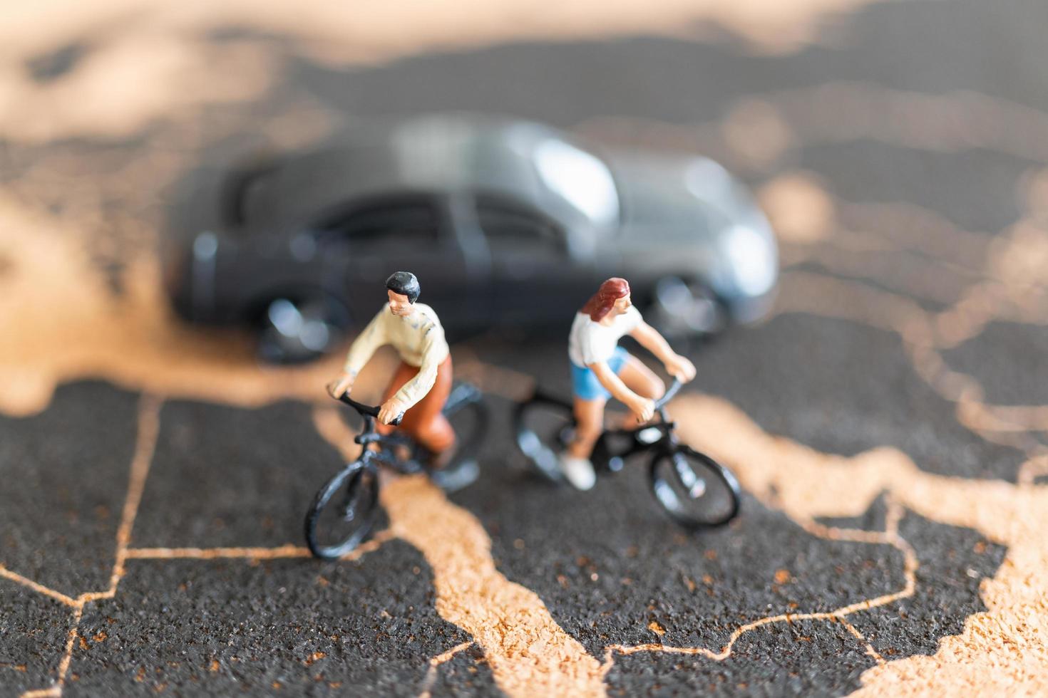 viajantes em miniatura com bicicletas no fundo de um mapa-múndi foto