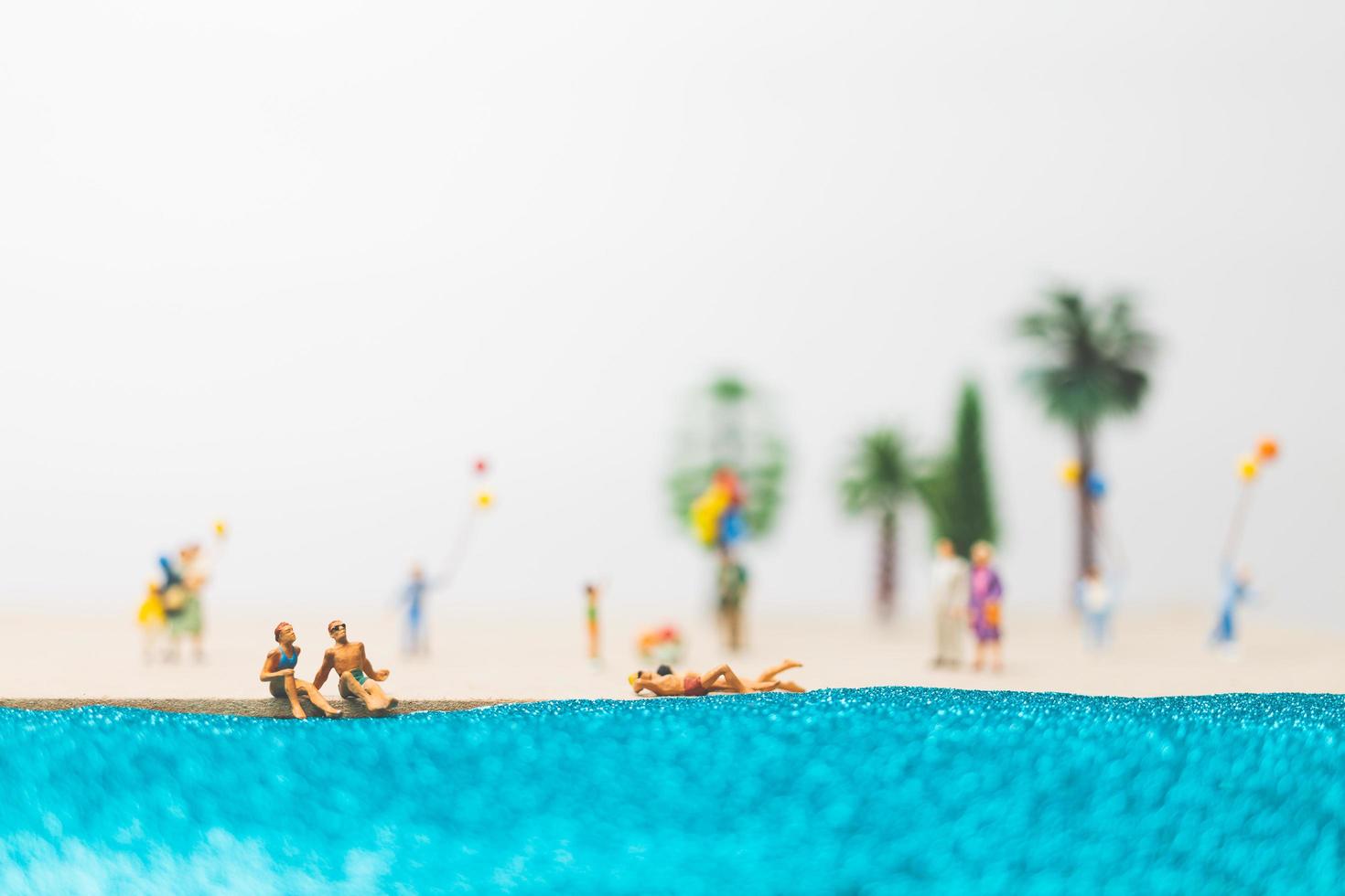 pessoas em miniatura aproveitando as férias de verão na praia foto