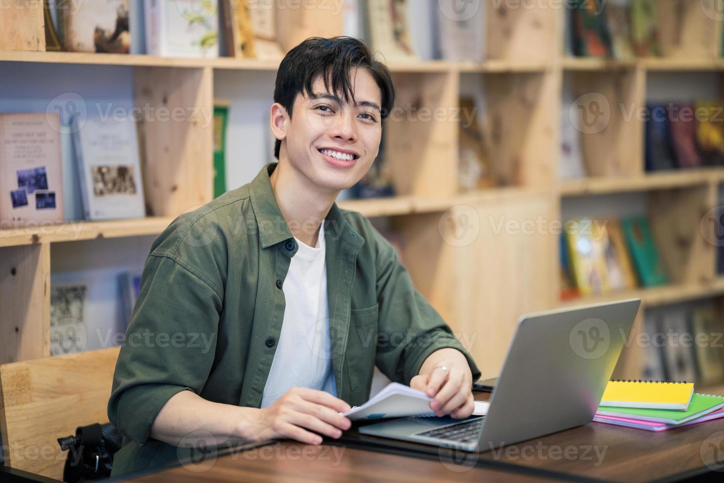 jovem ásia homem estudando às biblioteca foto