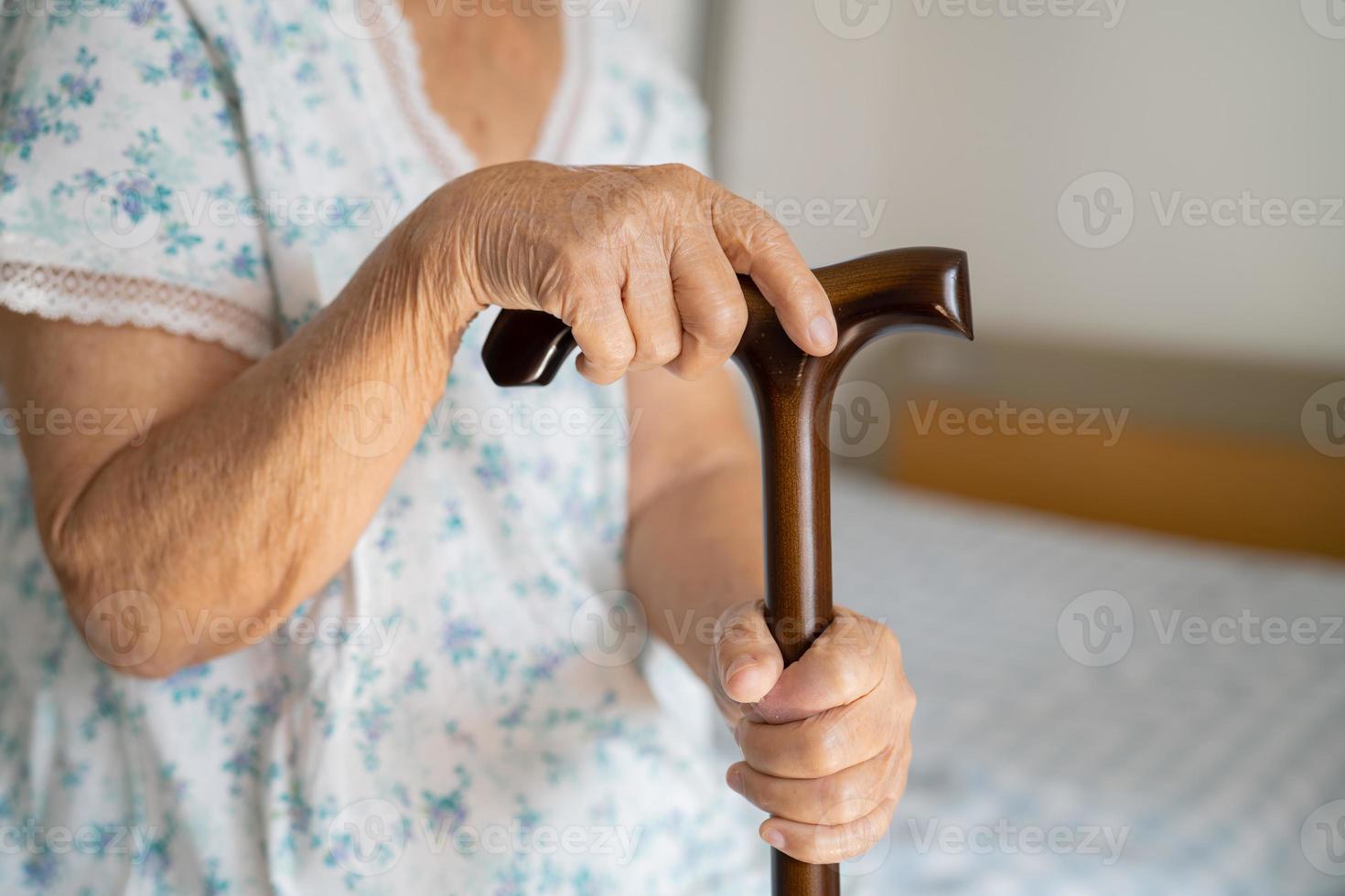 ásia idosos incapacidade mulher segurando caminhando grudar, madeira bengala, volta lidar, caminhando ajuda para Socorro para andar. foto