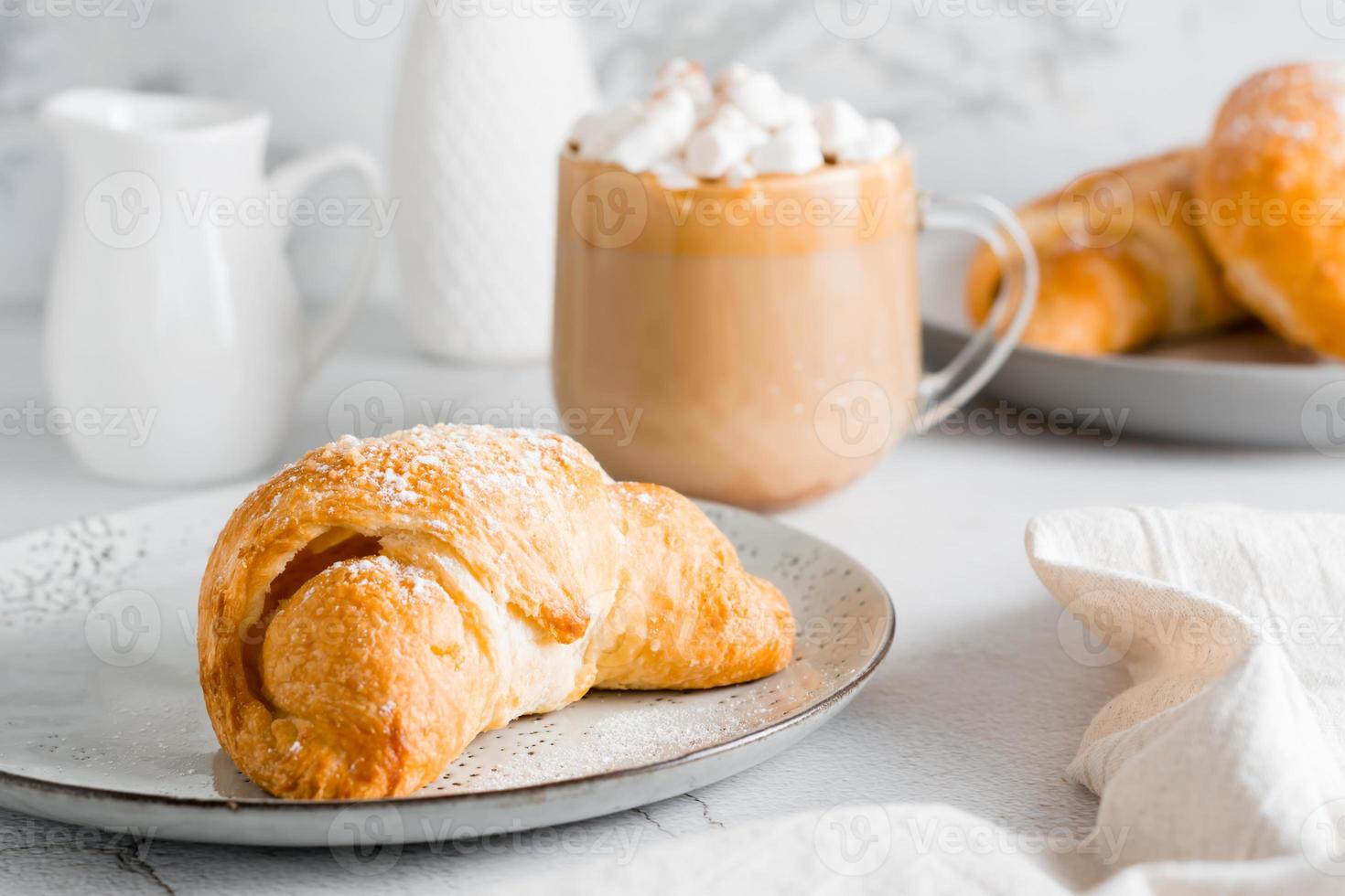 fresco croissant em uma prato e uma grande copo do café em a mesa. caseiro café da manhã estilo de vida. fechar-se foto