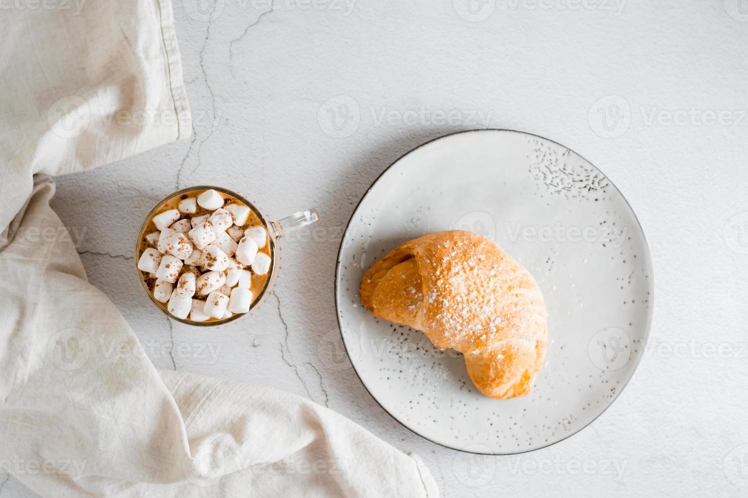 fresco croissant em uma prato e uma grande copo do café em a mesa. caseiro café da manhã estilo de vida. topo Visão foto