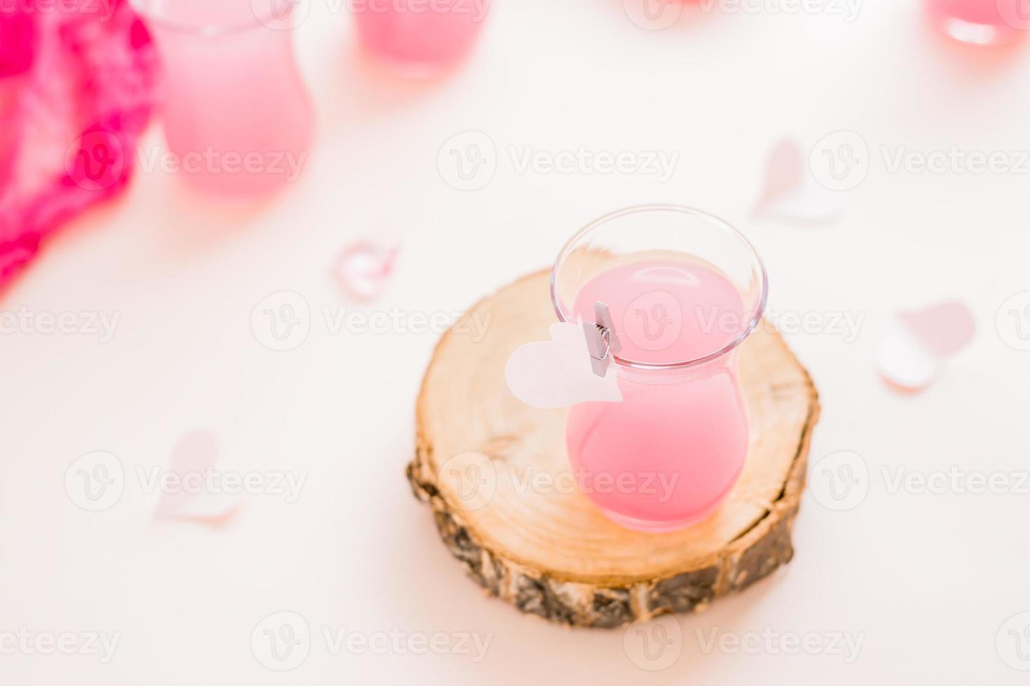 Rosa coquetel dentro uma vidro em uma árvore tronco e papel corações em uma Rosa fundo. bebidas para amantes foto