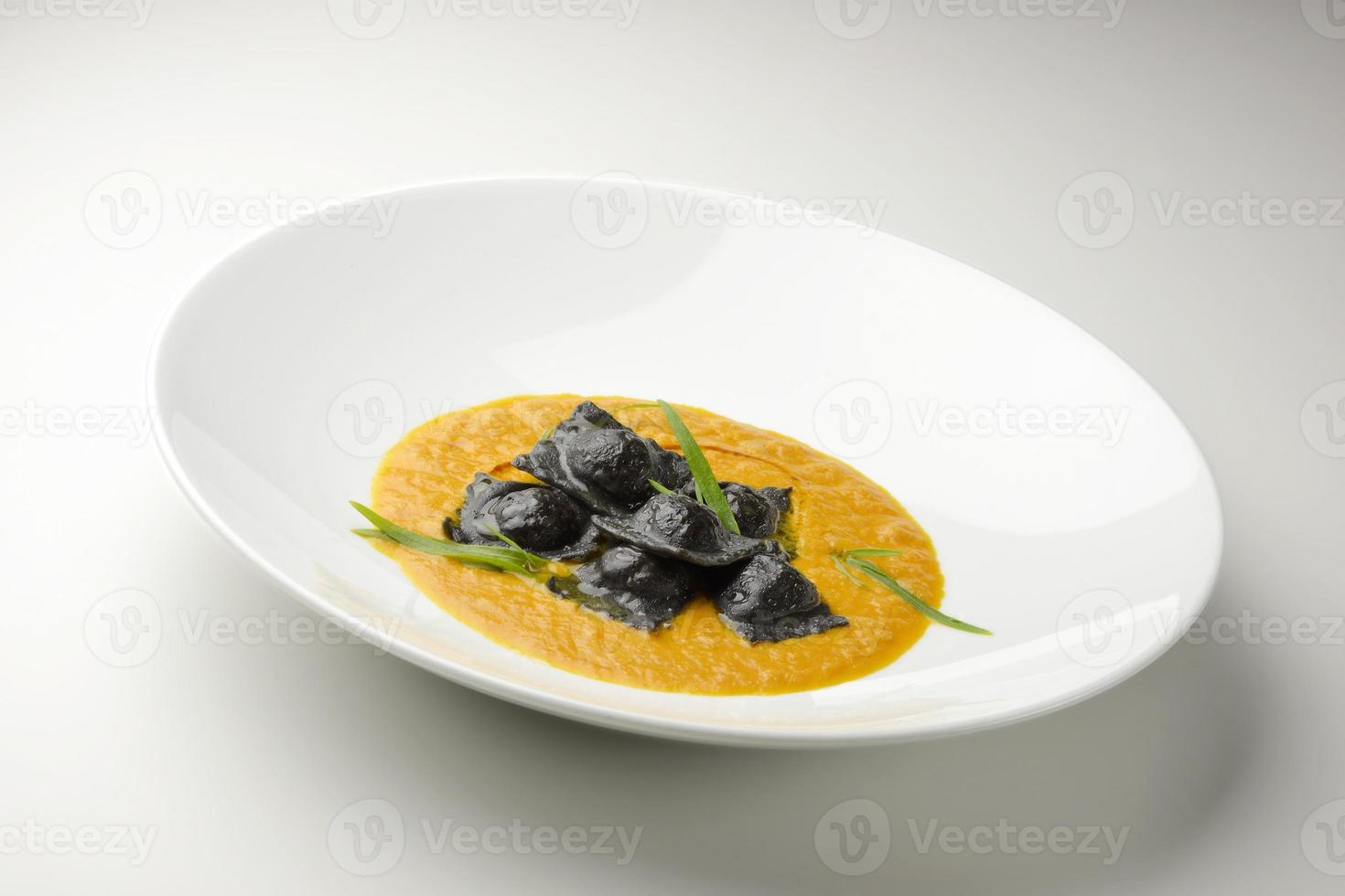 prato de massa preta com ravióli recheado com caldo de peixe foto