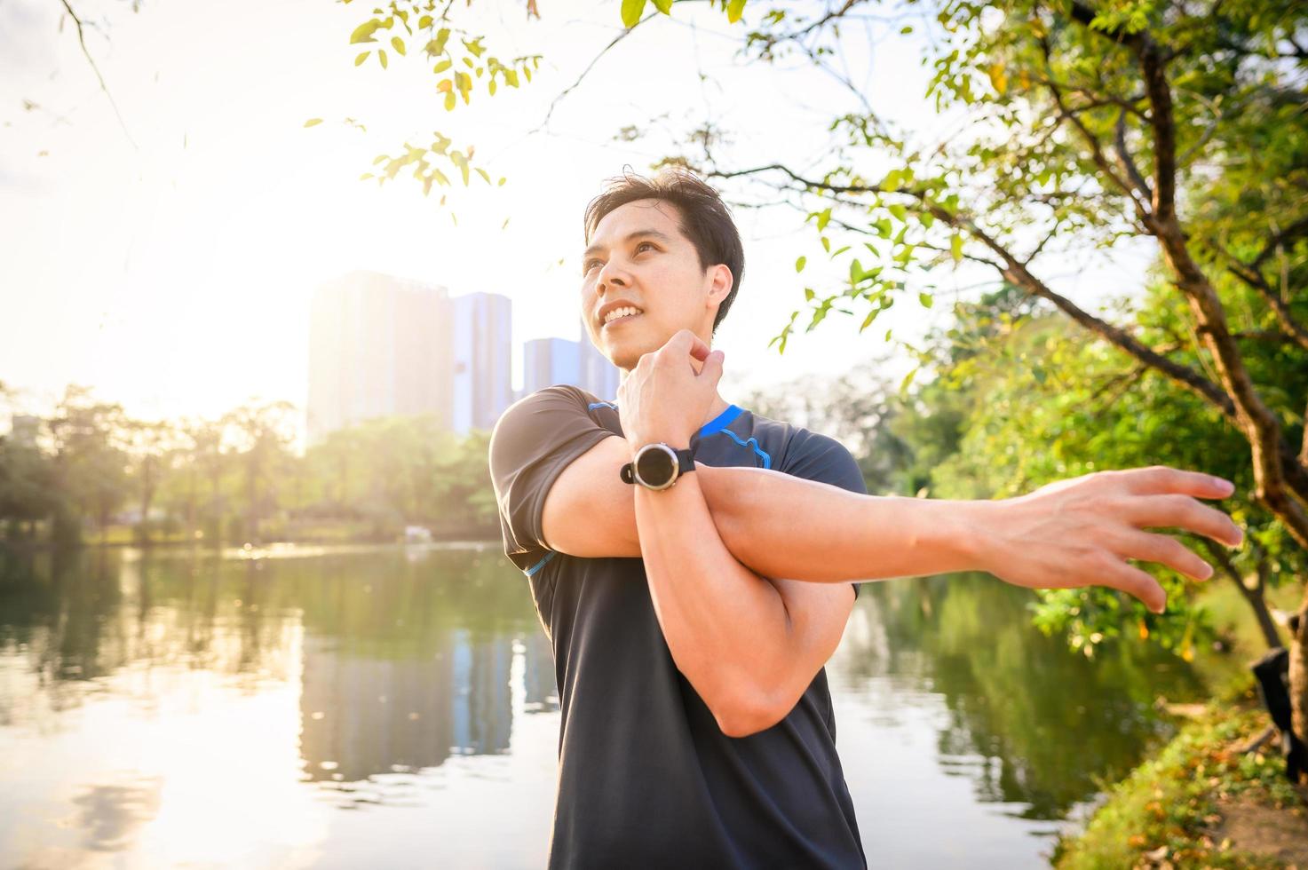 homem asiático esticando o ombro após terminar de correr foto