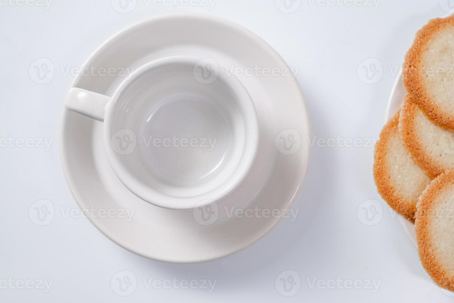 caneca de café branca vazia com biscoitos no fundo branco foto