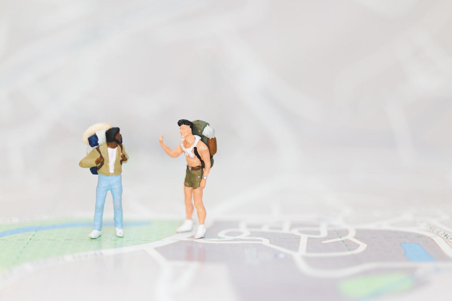 viajantes em miniatura com mochilas andando em um mapa, conceito de viagem e aventura foto