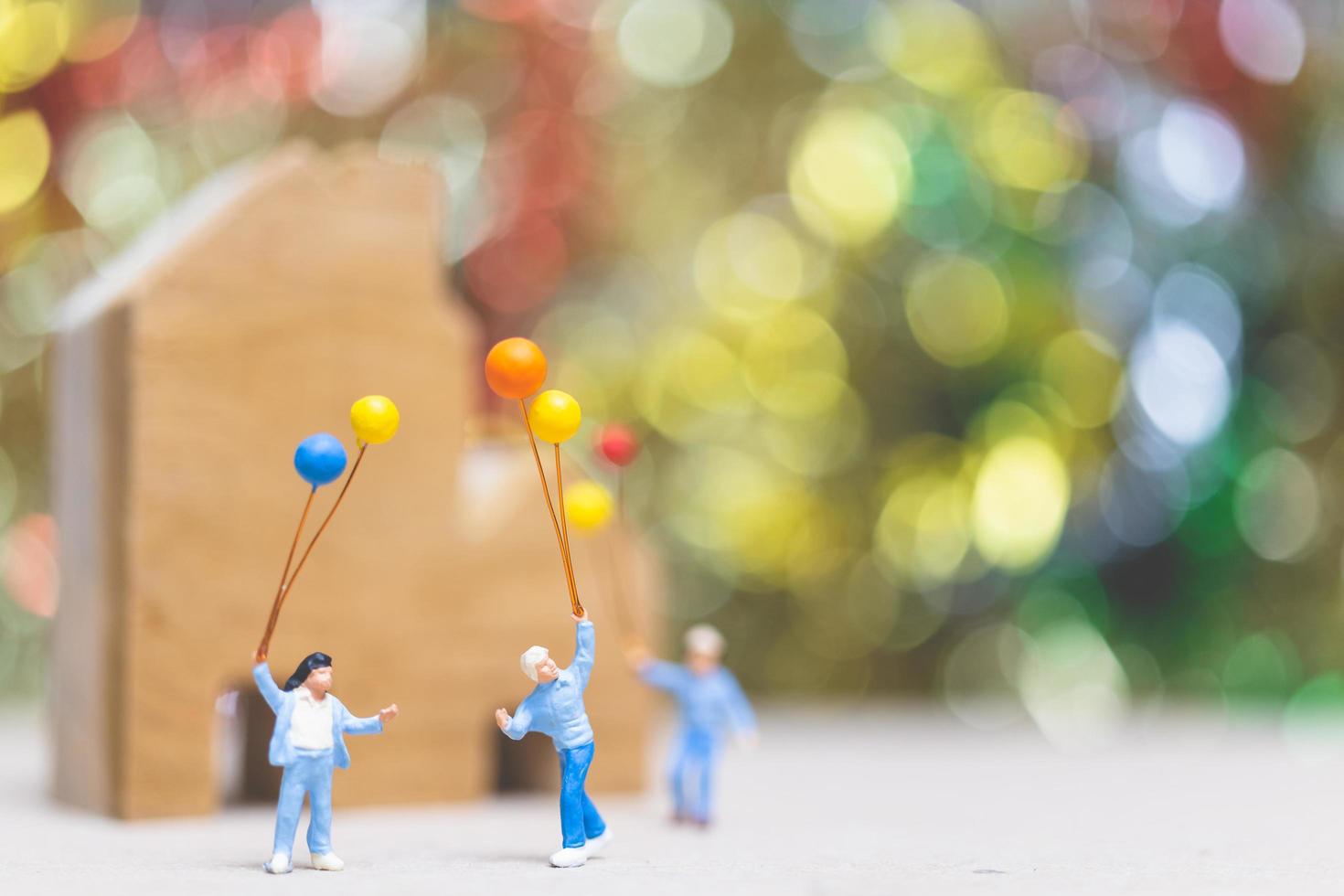 pessoas em miniatura segurando balões em um parque com um fundo colorido bokeh, relações familiares felizes e conceito de lazer despreocupado foto