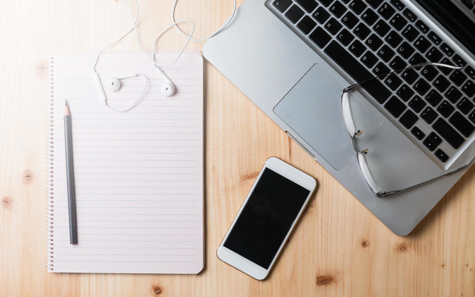 em branco caderno com lápis e computador portátil foto