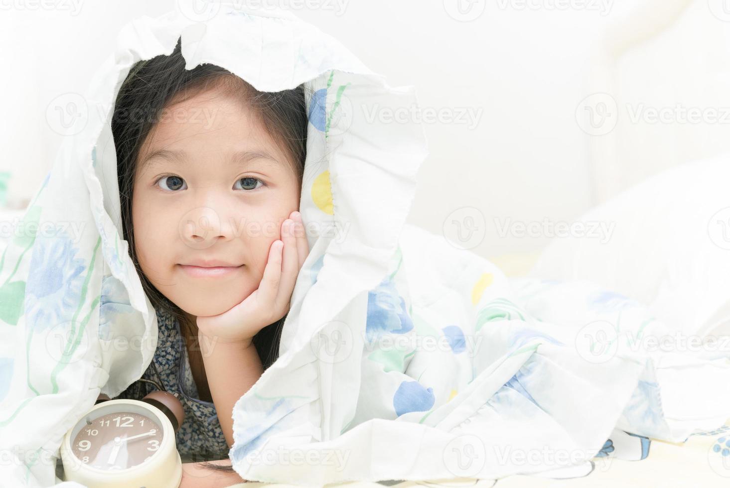 adorável menina acordada em sua cama foto