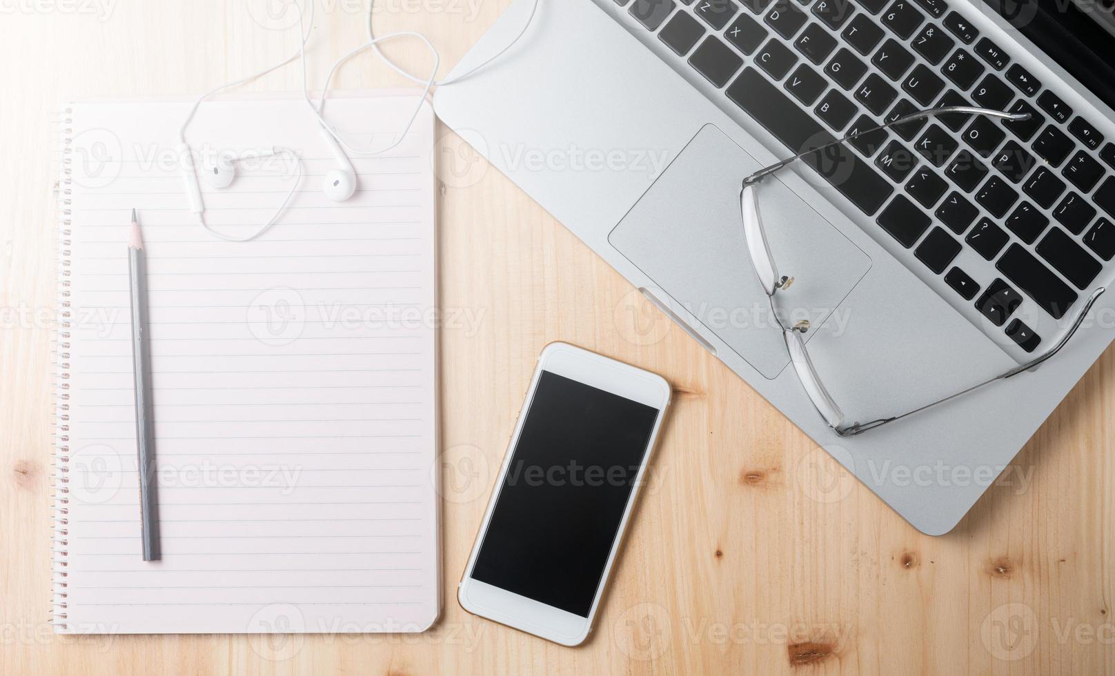 em branco caderno com Smartphone e computador portátil foto