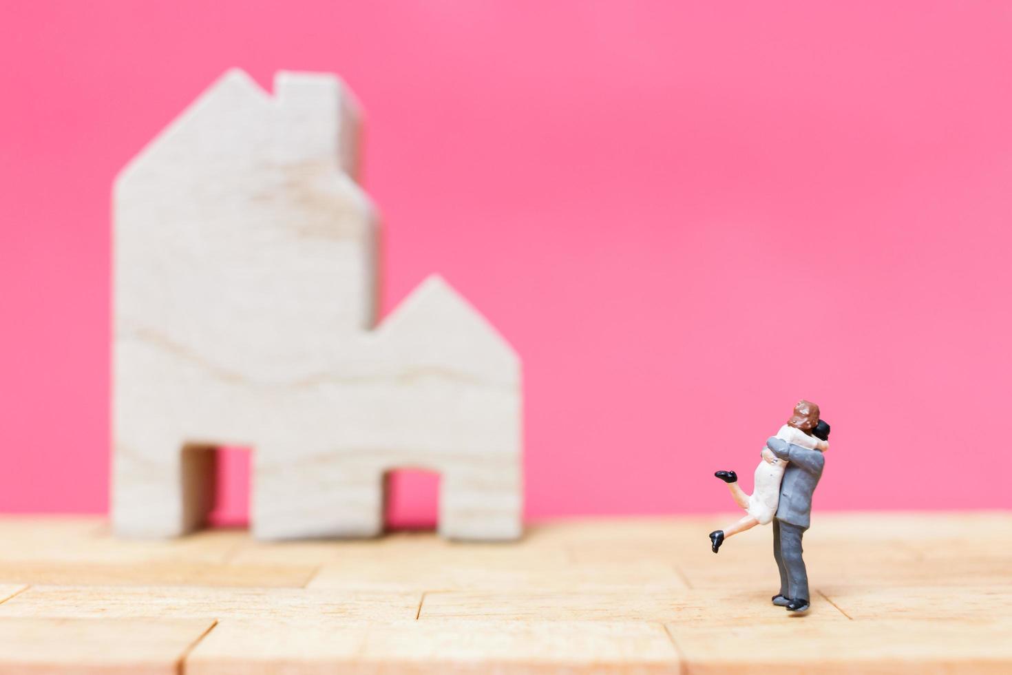 casal em miniatura com casas em um fundo rosa, conceito de dia dos namorados foto