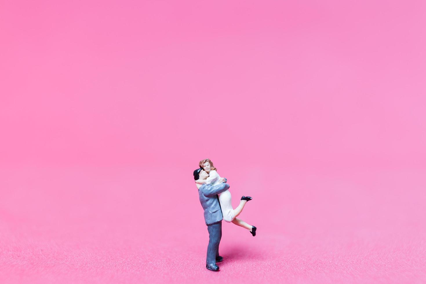 casal em miniatura se abraçando em um fundo rosa, conceito de dia dos namorados foto