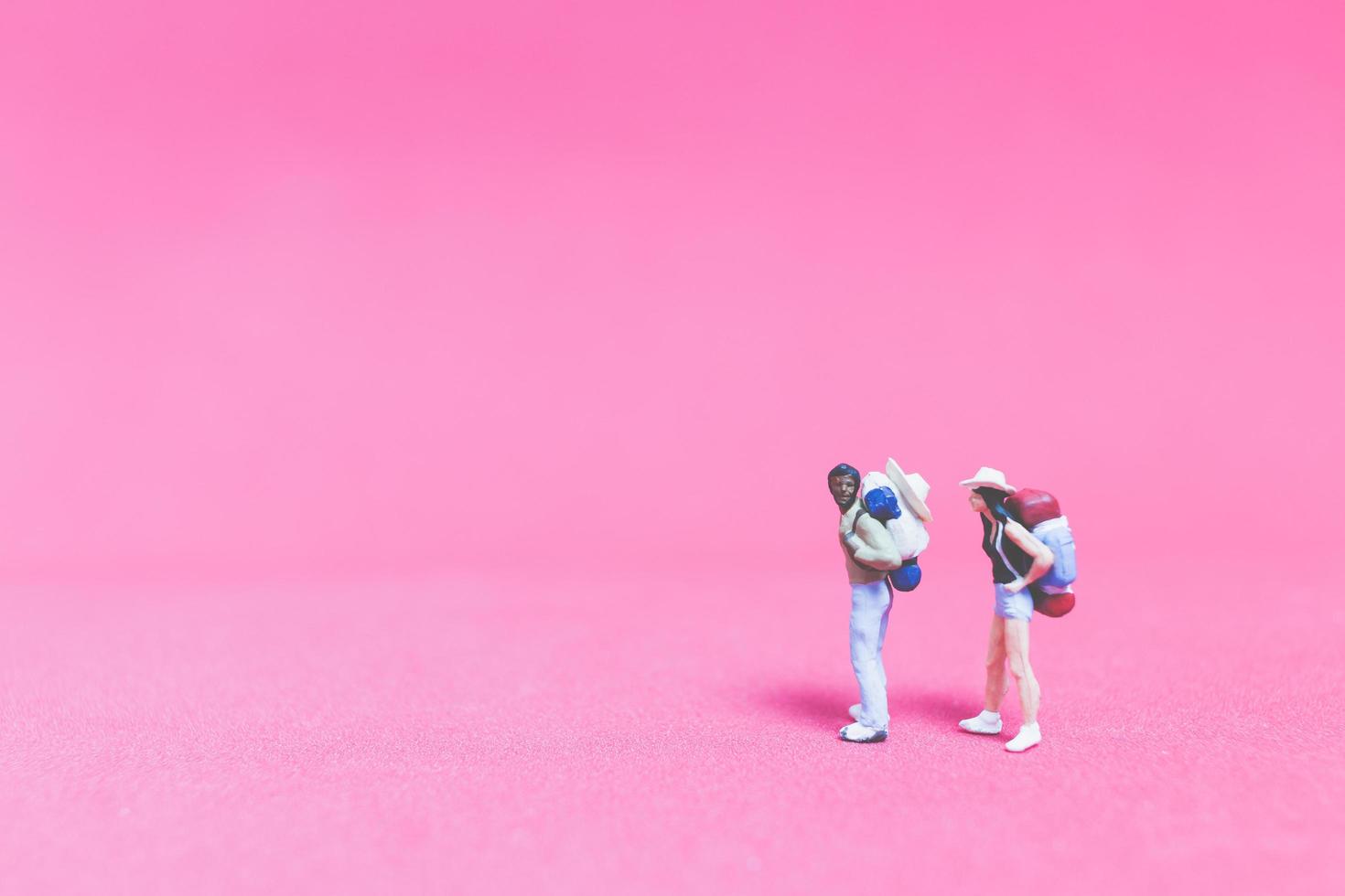casal de viajantes em miniatura em um fundo rosa foto