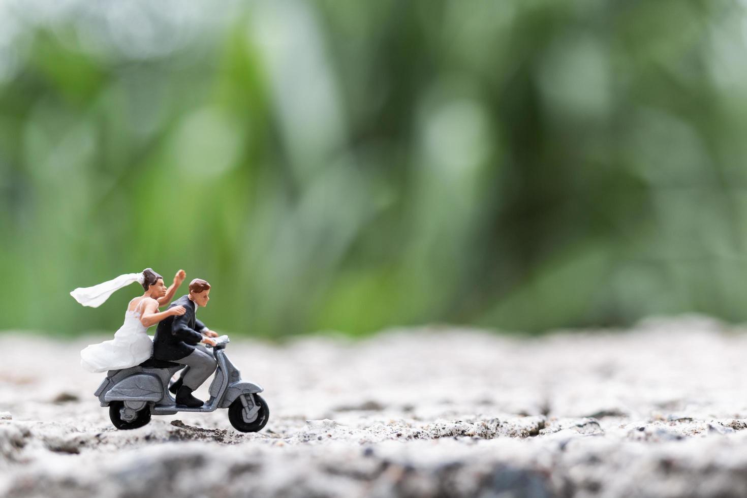 casal em miniatura andando de moto em um fundo borrado da natureza foto