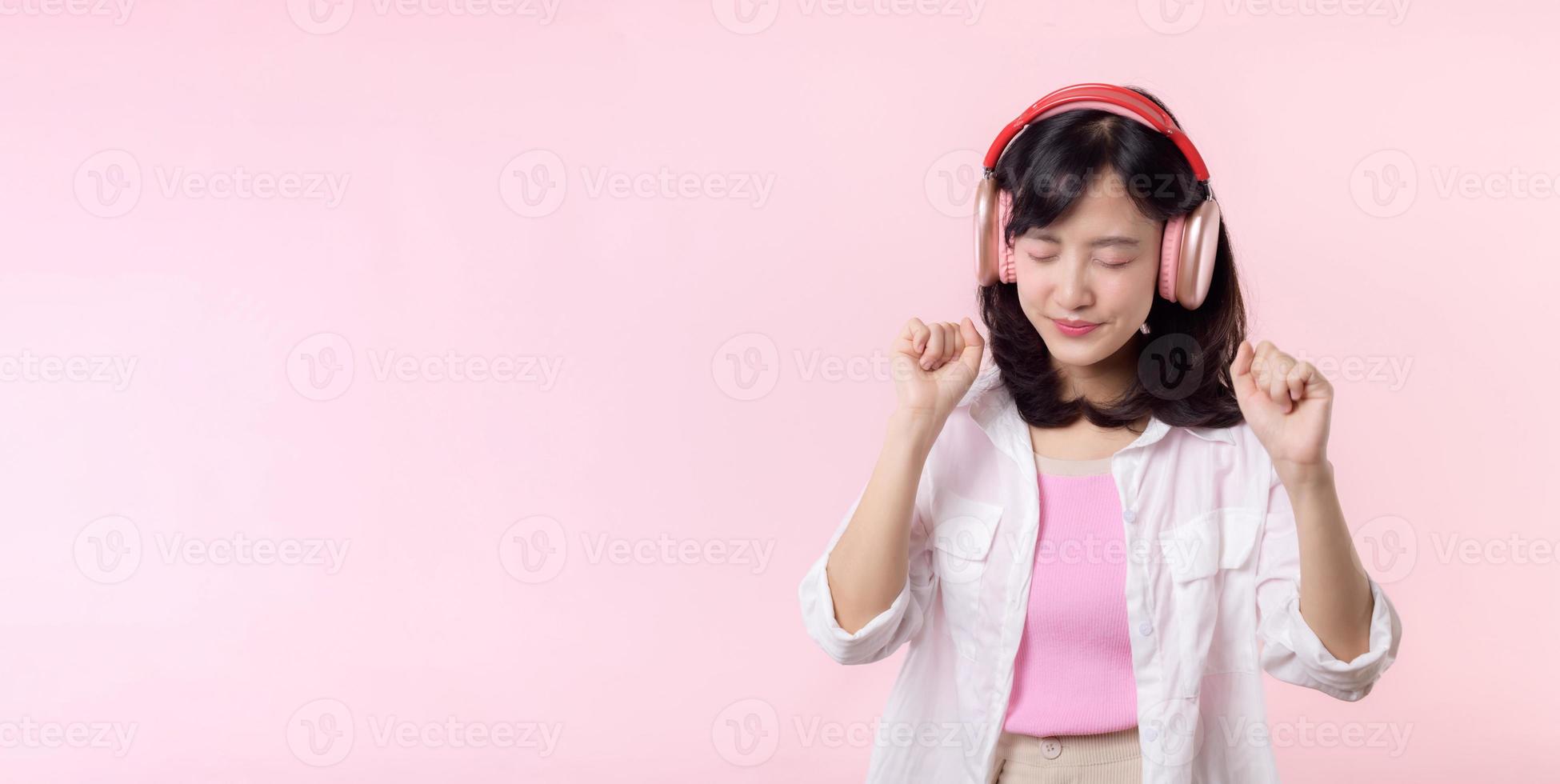 sorrir bonita ásia modelo pessoa ouço música música e apreciar dança com sem fio fone de ouvido conectados audio rádio som. positivo Diversão saiu alegre juventude fêmea mulher em Rosa isolado fundo estúdio foto