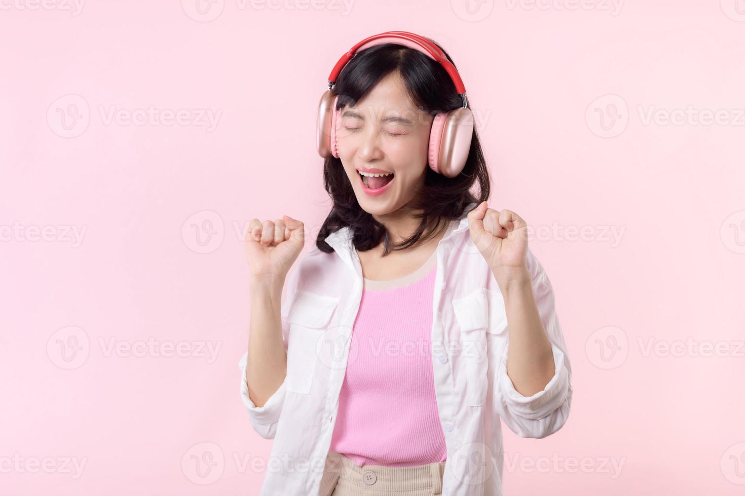 sorrir bonita ásia modelo pessoa ouço música música e apreciar dança com sem fio fone de ouvido conectados audio rádio som. positivo Diversão saiu alegre juventude fêmea mulher em Rosa isolado fundo estúdio foto