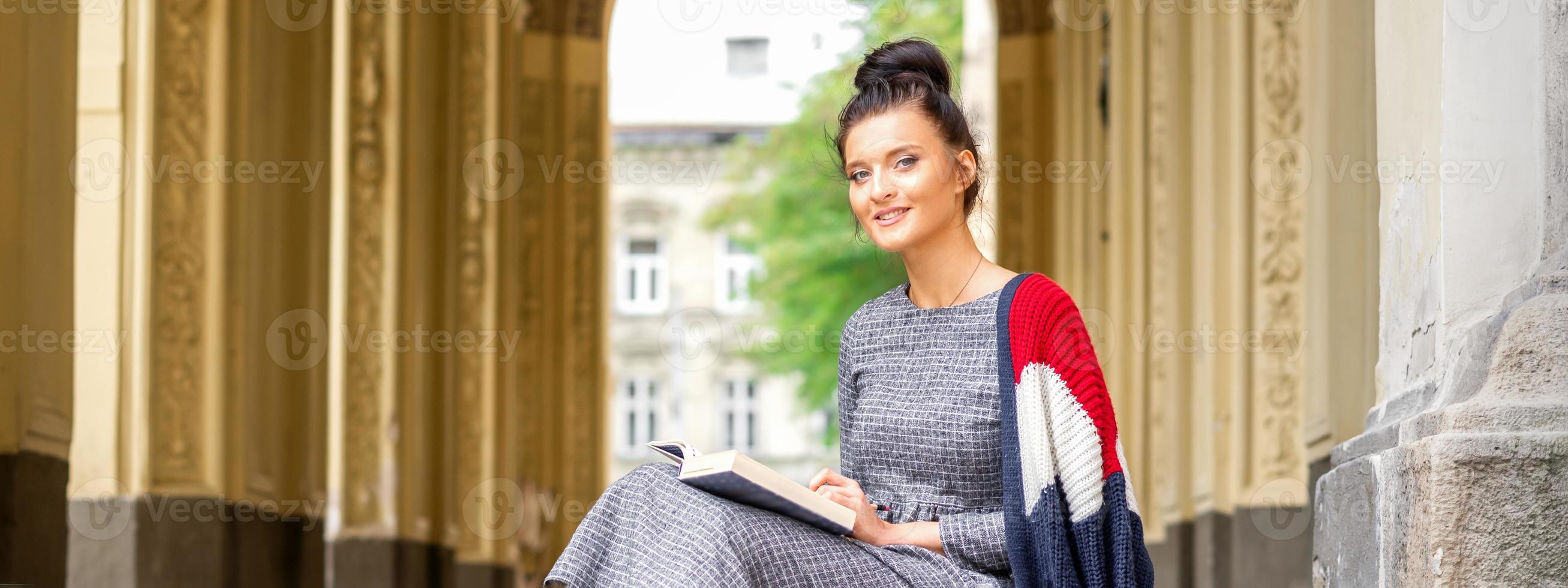 aluna com livro sentado em escadas foto