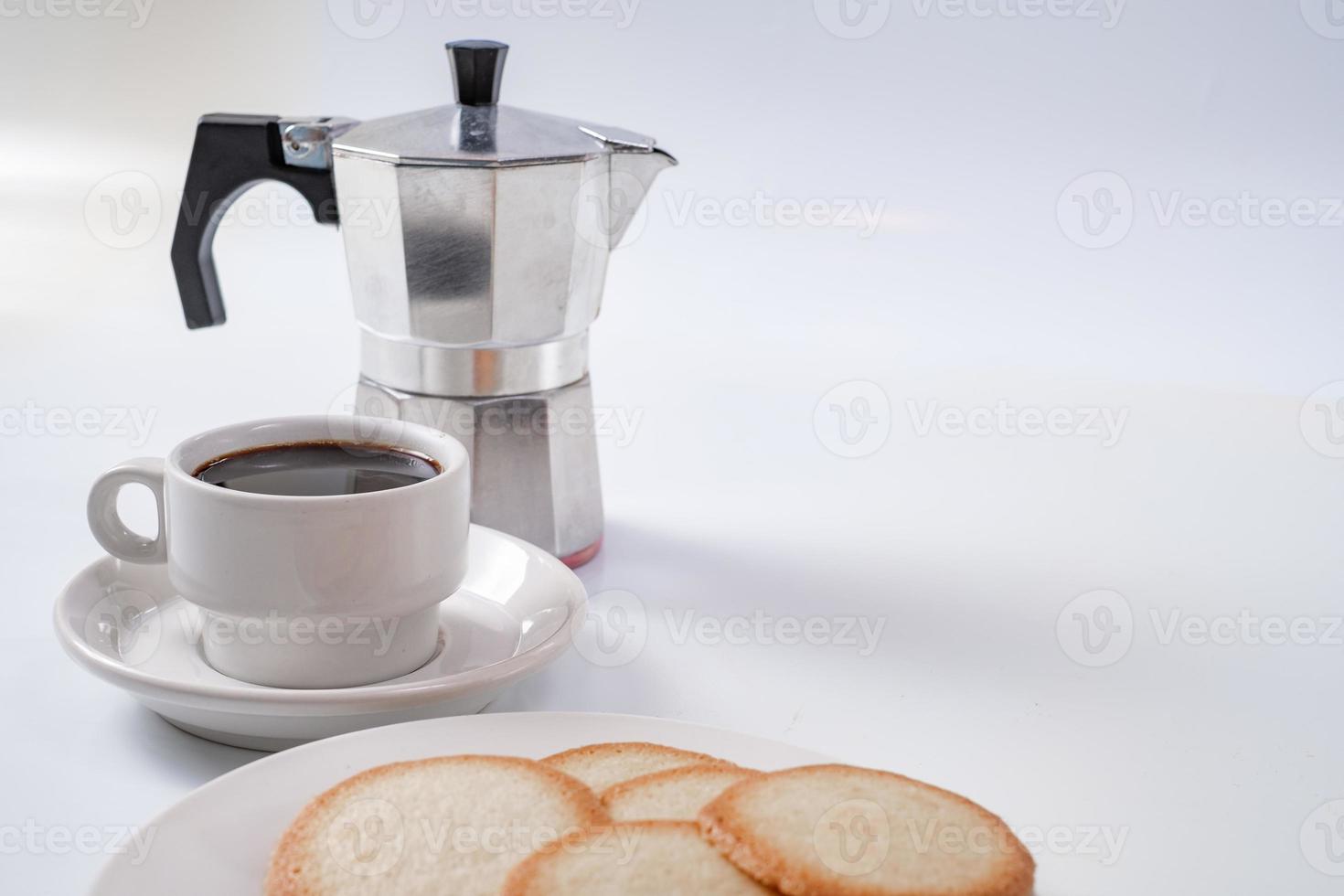 cafeteira com xícara branca de café da manhã e biscoitos foto