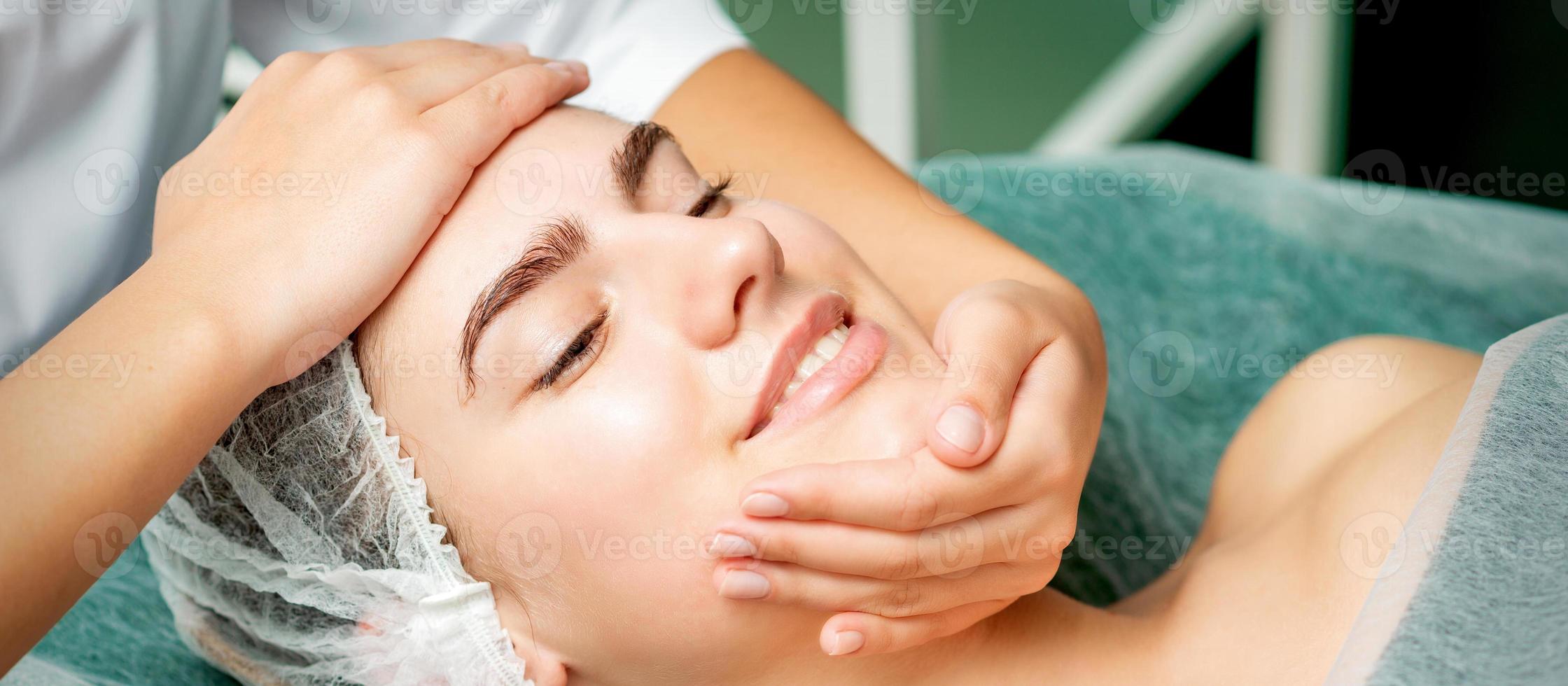 jovem mulher obtendo facial massagem foto