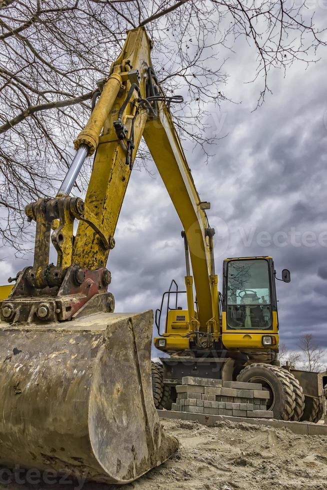 grande amarelo parado escavadora às a construção local. vertical Visão foto