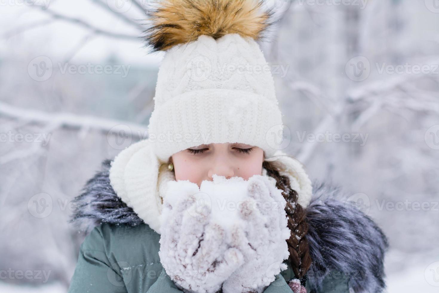 uma menina dentro caloroso roupas detém neve dentro dela mãos dentro luvas dentro uma inverno parque. inverno estilo de vida retrato foto