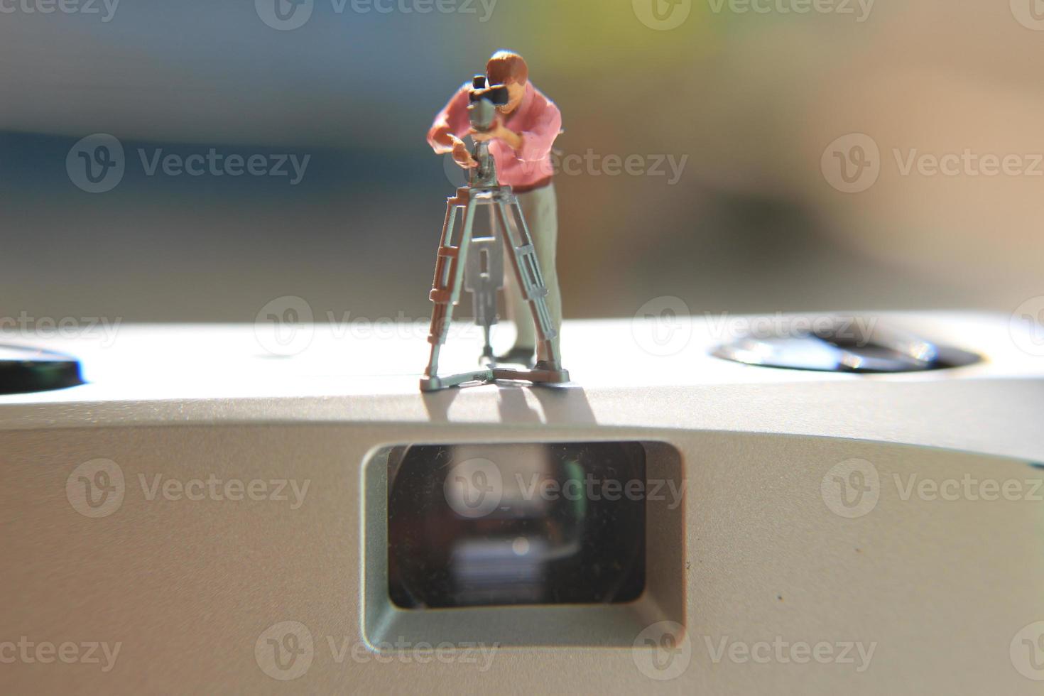 miniatura figura do uma cinegrafista gravação em a analógico Câmera. foto