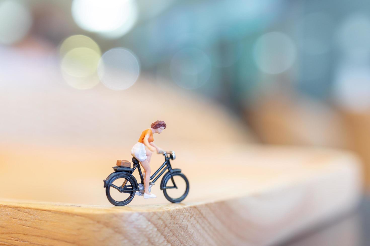 pessoa em miniatura pedalando em uma ponte de madeira, conceito de saúde foto