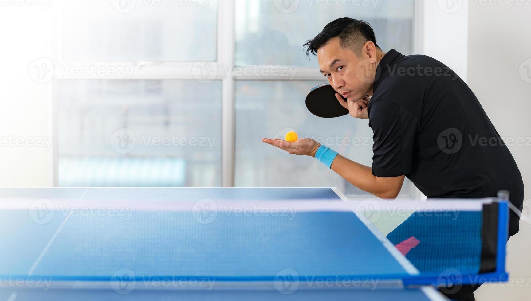 masculino jogando tênis de mesa com raquete e bola em um ginásio esportivo foto