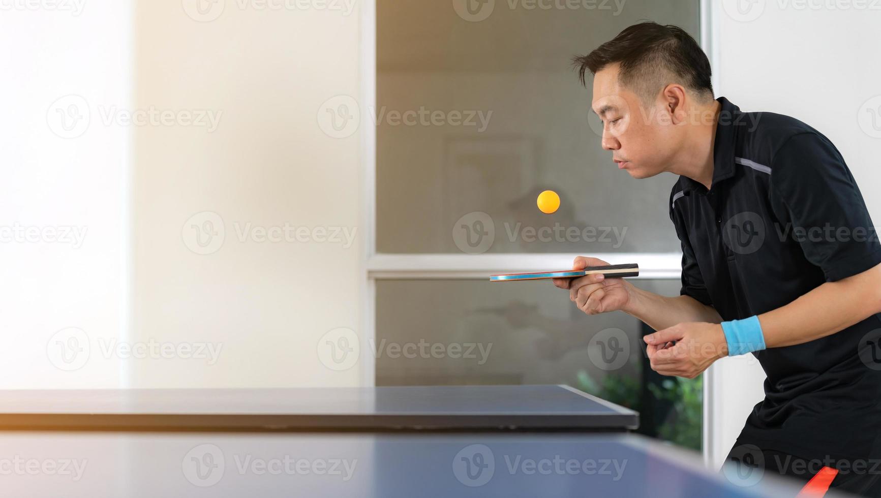 masculino jogando tênis de mesa com raquete e bola em um ginásio esportivo foto