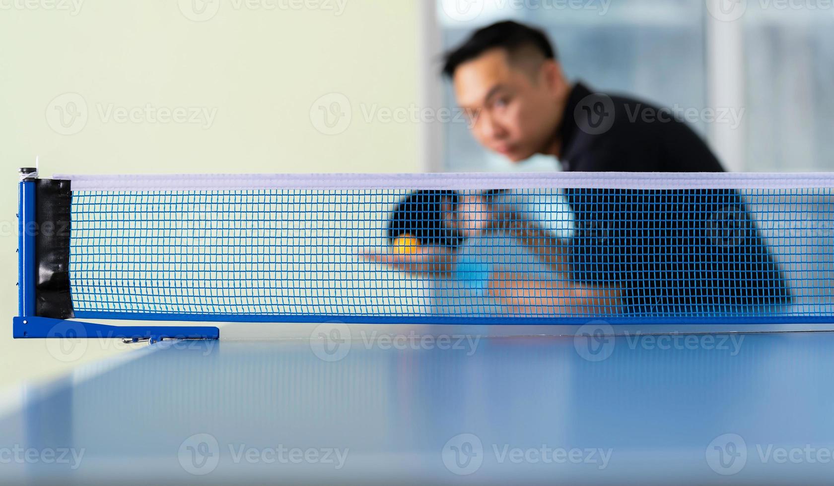 masculino jogando tênis de mesa com raquete e bola em um ginásio esportivo foto