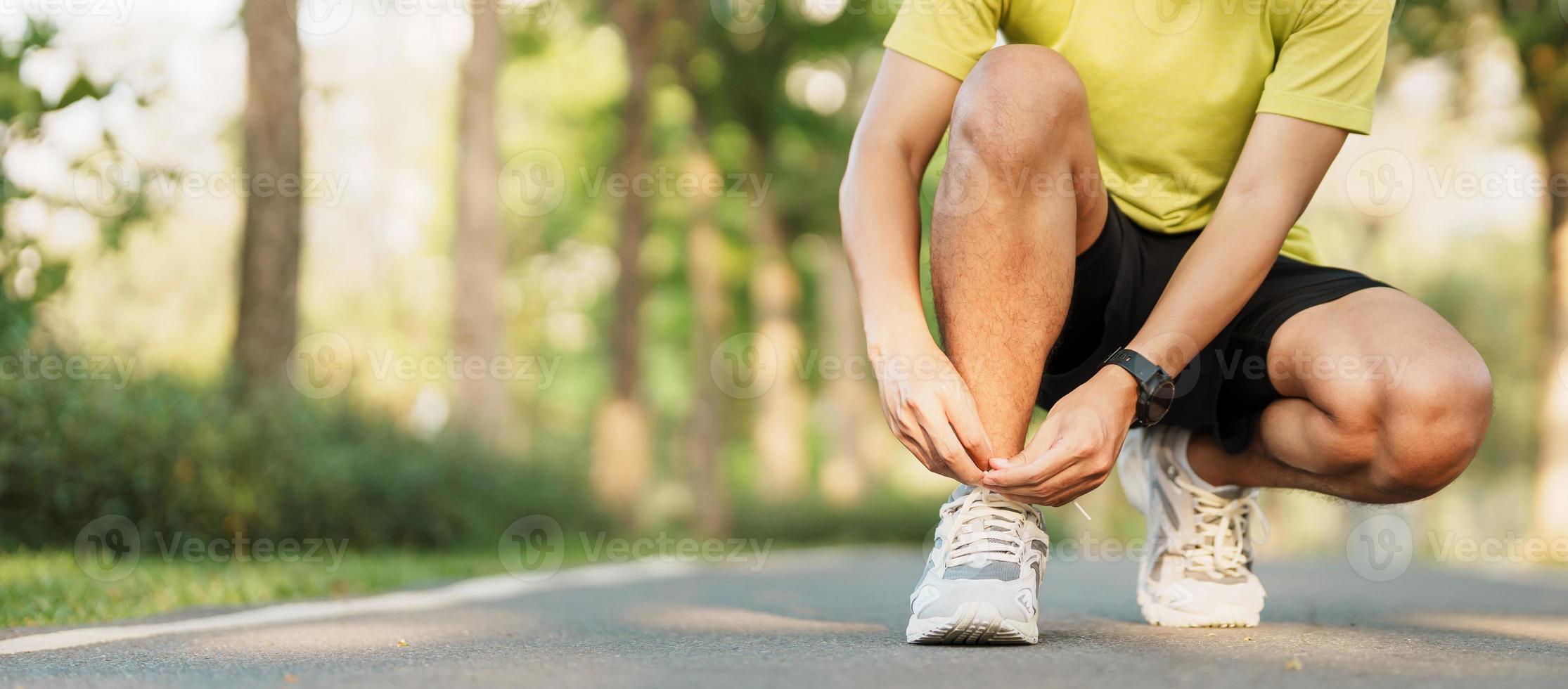 jovem atleta homem amarrar corrida sapatos dentro a parque ar livre, masculino corredor pronto para corrida em a estrada fora, ásia ginástica caminhando e exercício em trilha dentro manhã. bem estar e esporte conceitos foto