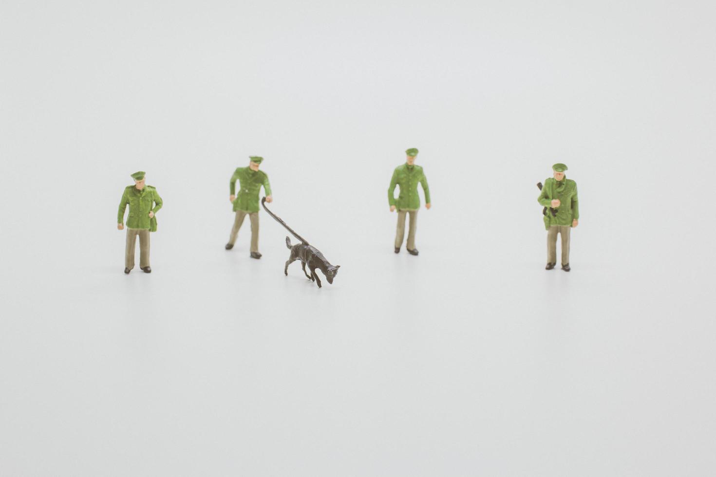 policiais em miniatura com cães policiais farejando evidências em um fundo branco foto