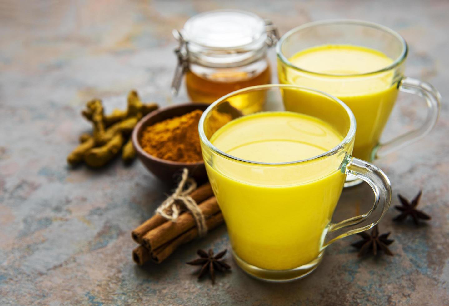 leite dourado com canela, cúrcuma, gengibre e mel sobre fundo de concreto foto