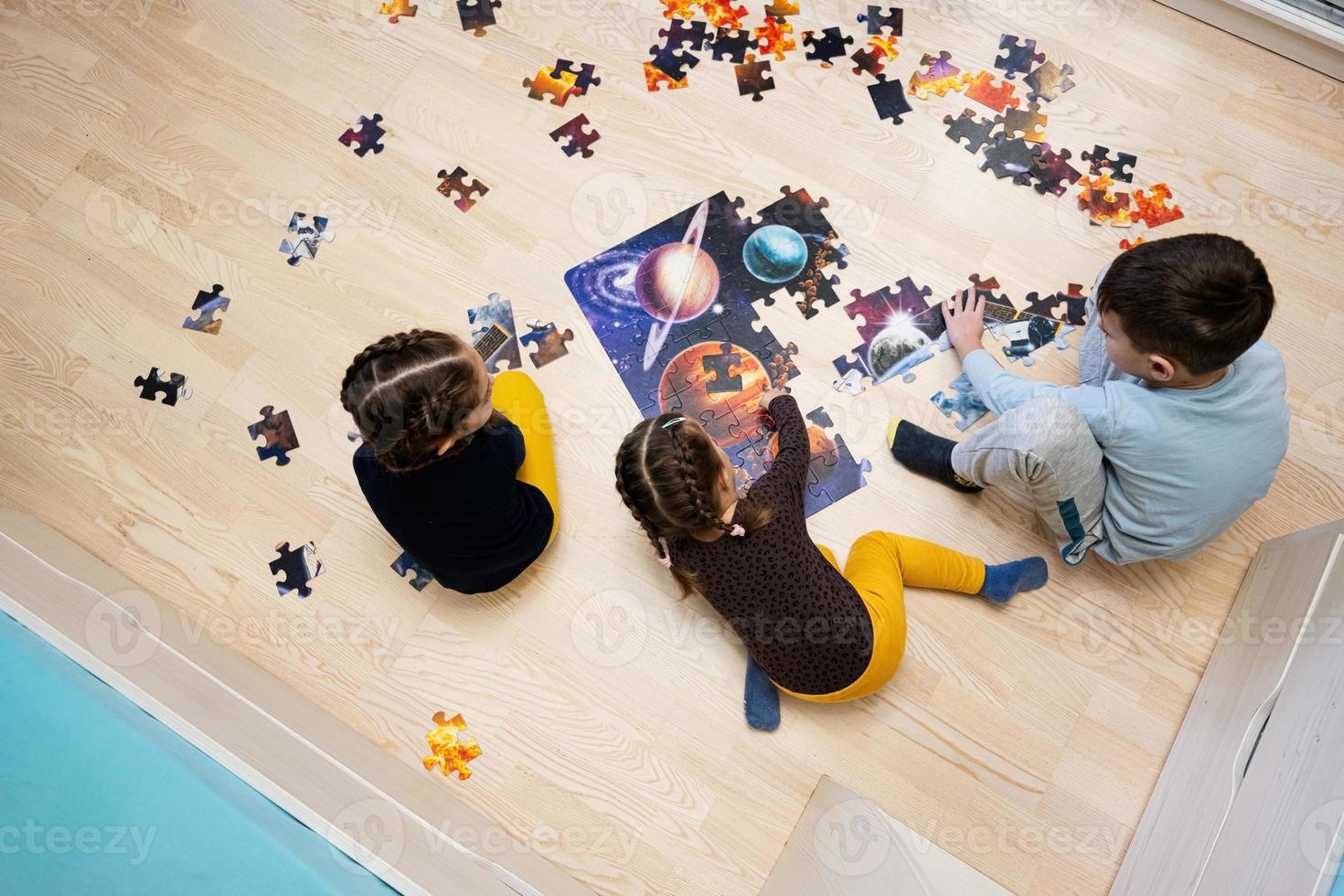 crianças conectando peças de quebra-cabeça em um quarto infantil no chão de casa. diversão em família atividade lazer. foto