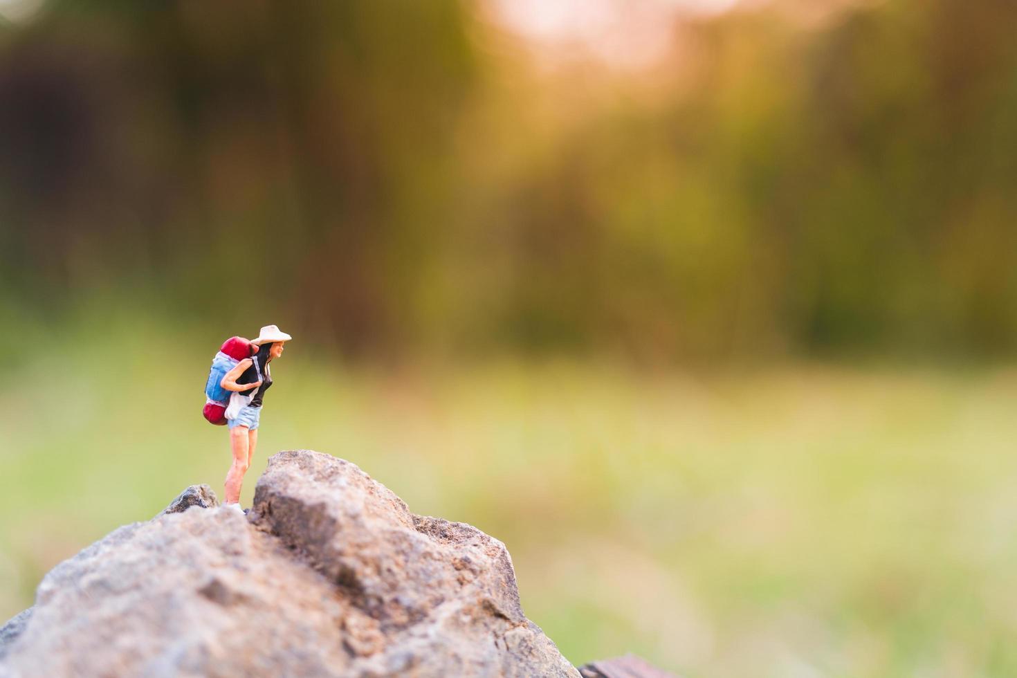 viajante em miniatura com uma mochila caminhando na natureza, conceito de viagem e aventura foto