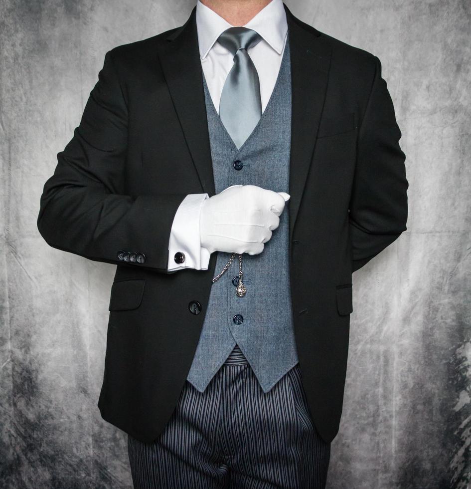 retrato de mordomo ou concierge de hotel em terno escuro e luvas brancas ansioso para servir. conceito de hospitalidade elegante e cortesia profissional. foto