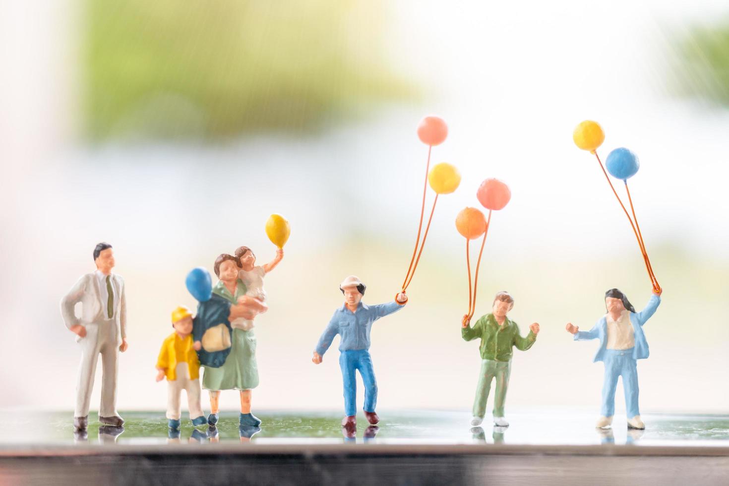 família em miniatura com balões, relações familiares felizes e conceito de lazer despreocupado foto