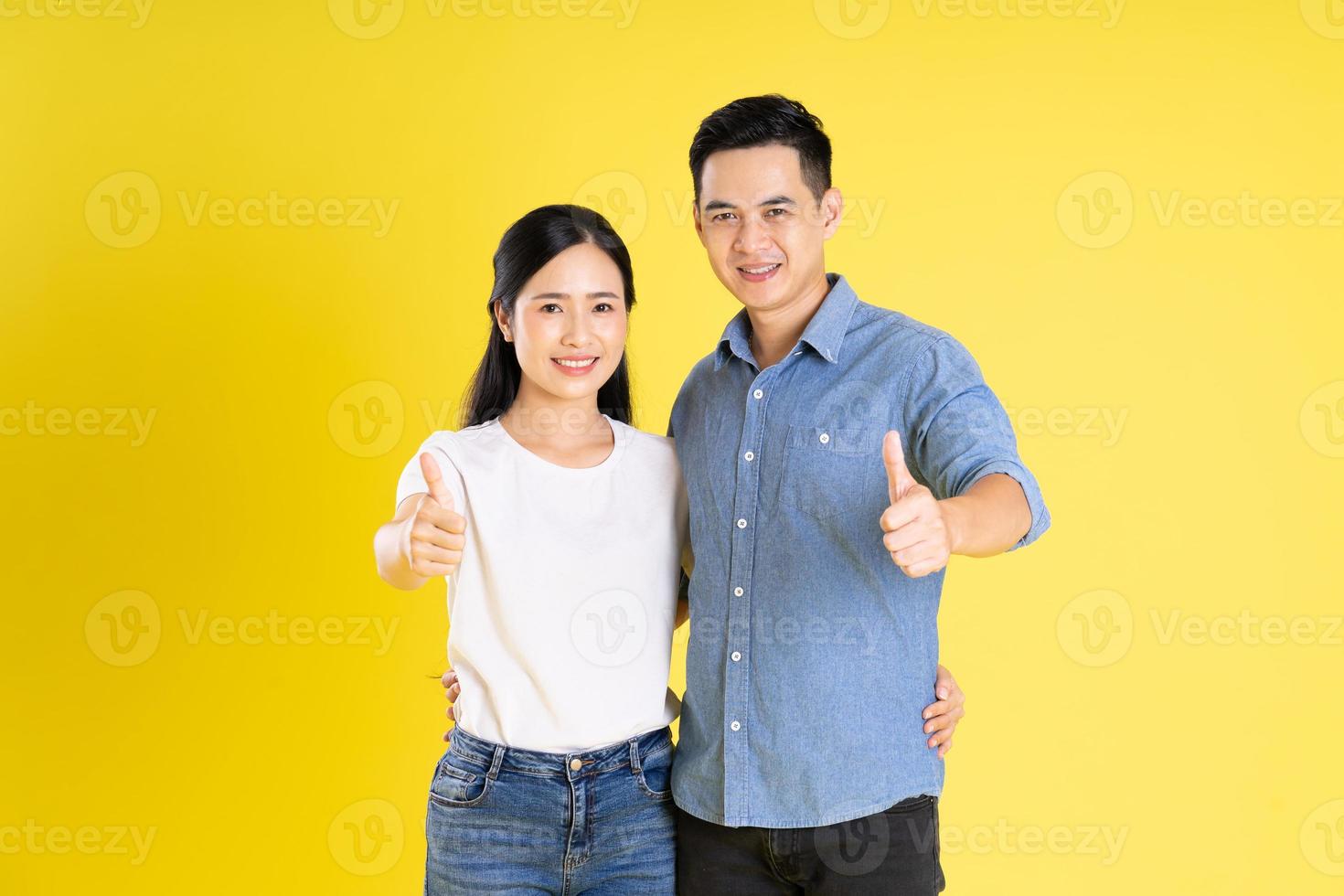 imagem de casal asiático posando em fundo amarelo foto