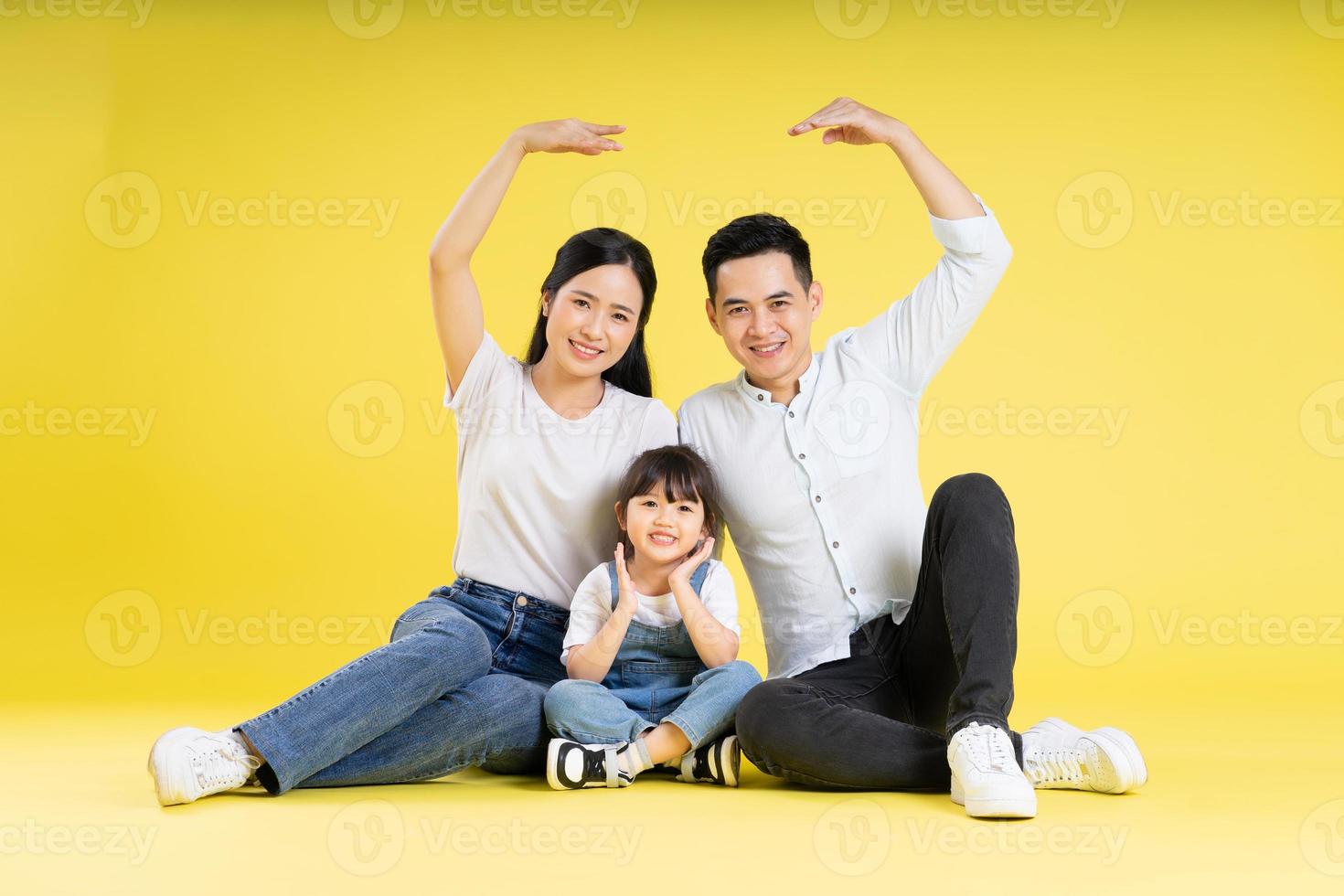 imagem da família asiática sentados juntos felizes e isolados em fundo amarelo foto