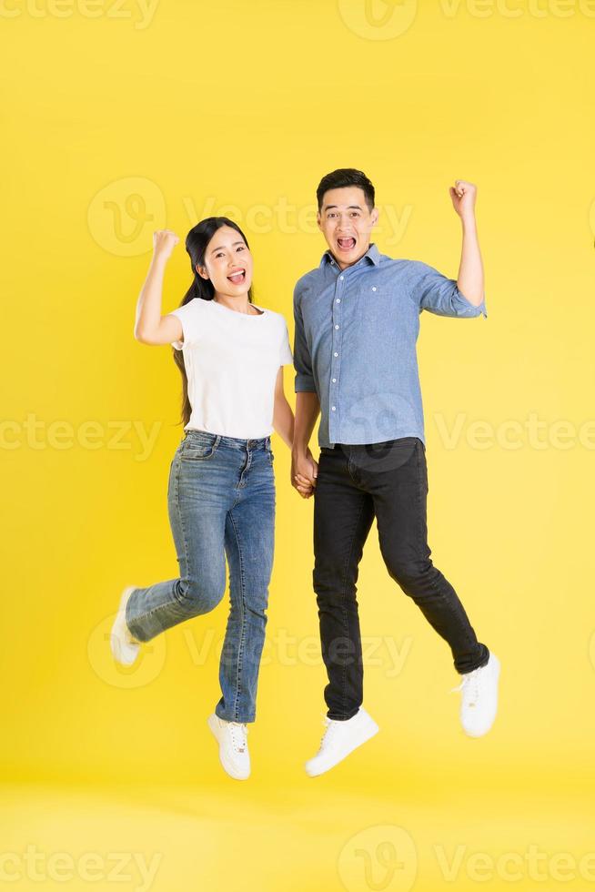 imagem de corpo inteiro de casal asiático posando em fundo amarelo foto